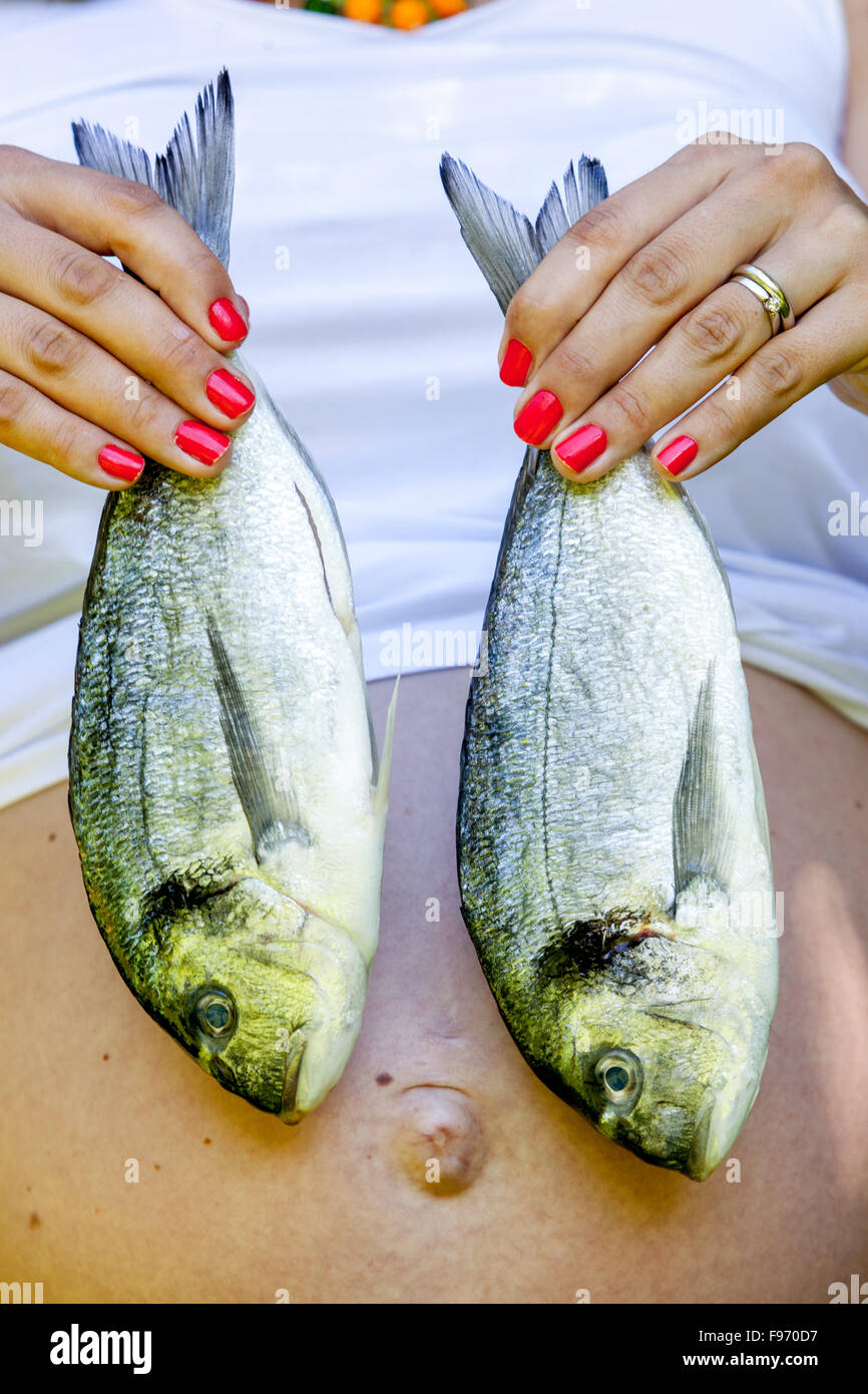 Frau mit zwei frischen Meeresbalken oder dorado-Fischen, Frau rote Nägel Stockfoto