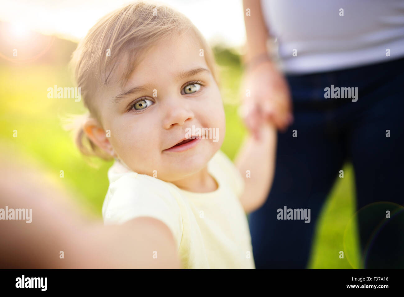 Kleines Mädchen mit Mutter im Hintergrund nehmen Selfie per Handy Stockfoto