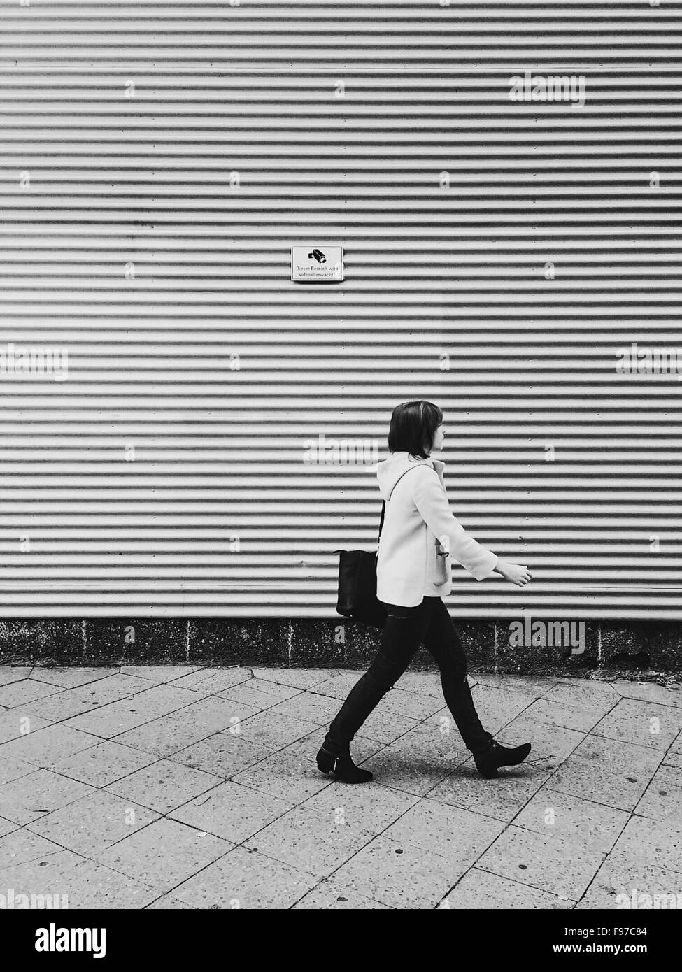 Seitenansicht der Frau zu Fuß auf dem Bürgersteig gegen Auslöser Stockfoto