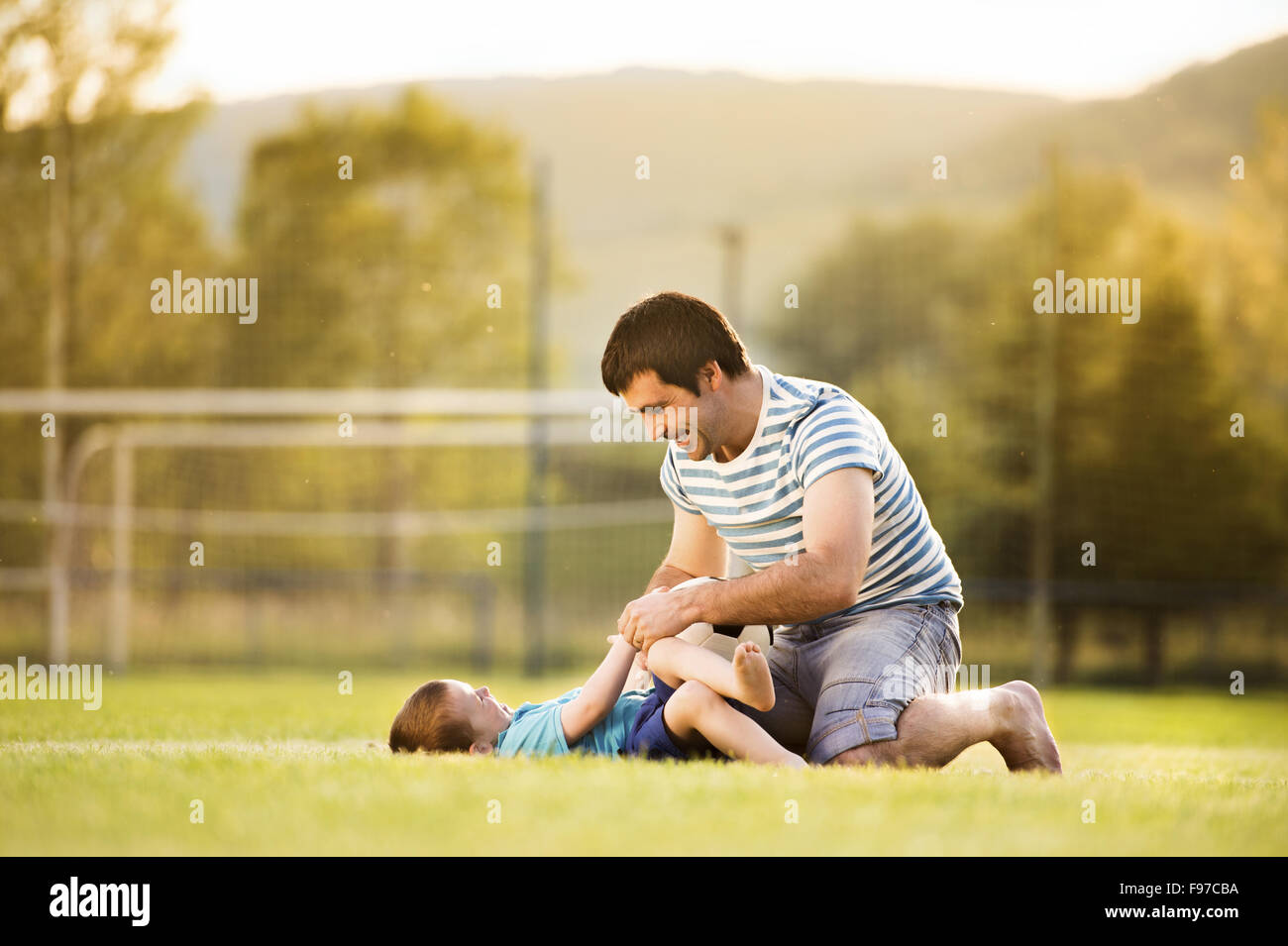 Junger Vater mit seinem kleinen Sohn Fußball spielen auf dem Fußballplatz Stockfoto