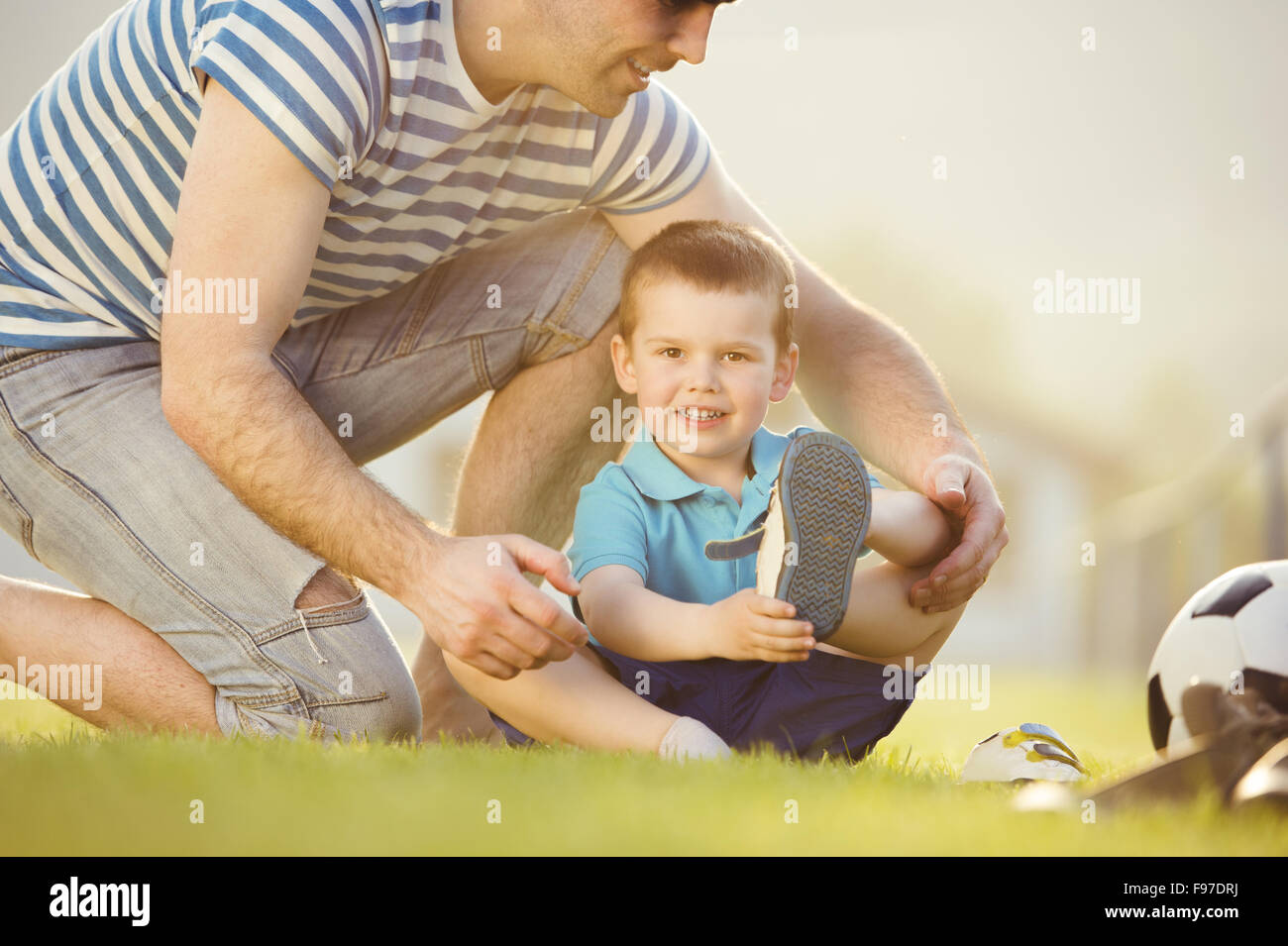 Junger Vater mit seinem kleinen Sohn ändern Schuhe auf Fußballplatz Stockfoto