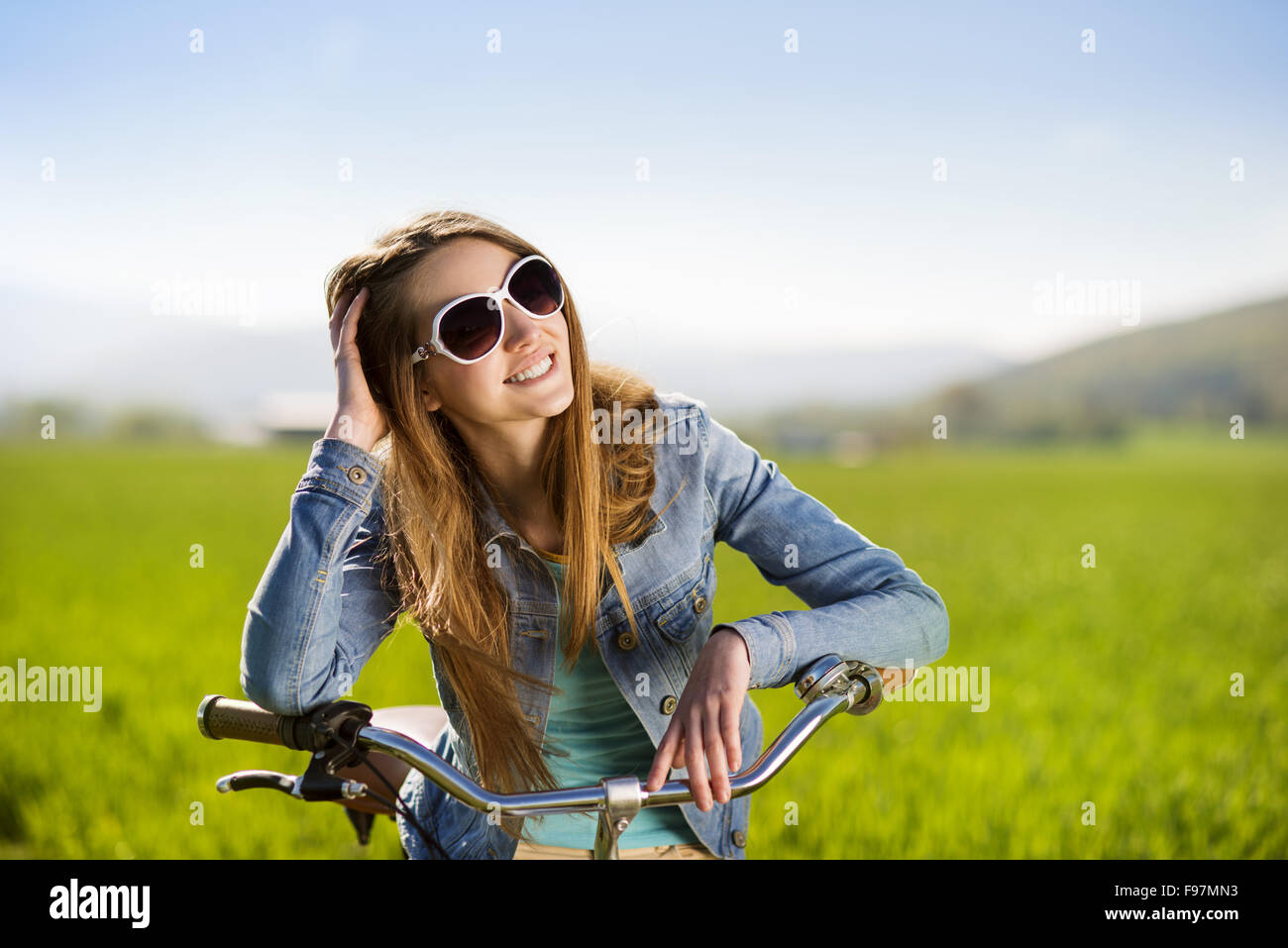 Hübsches junges Mädchen mit Fahrrad im grünen Bereich Stockfoto