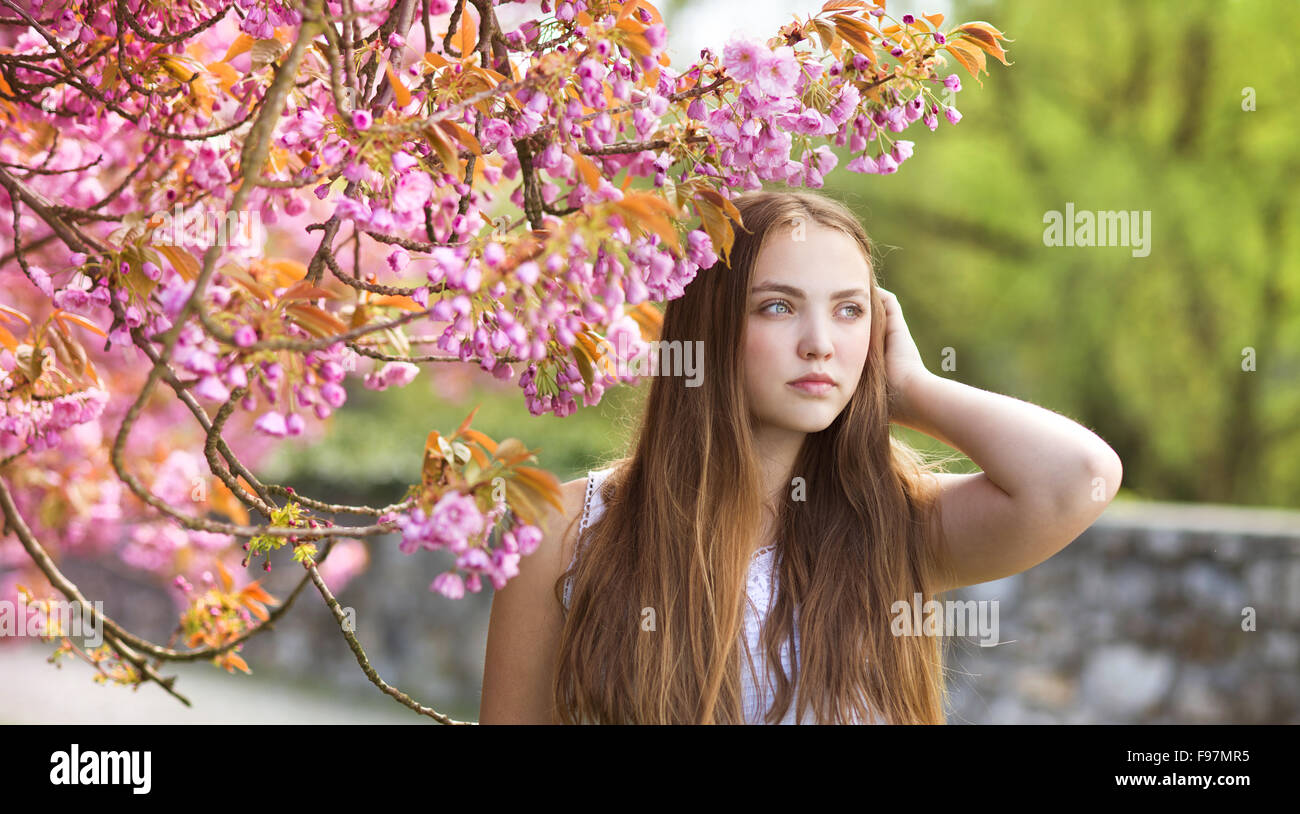 Schöne Mädchen im Frühlingsgarten unter den blühenden Bäumen mit rosa Blüten Stockfoto