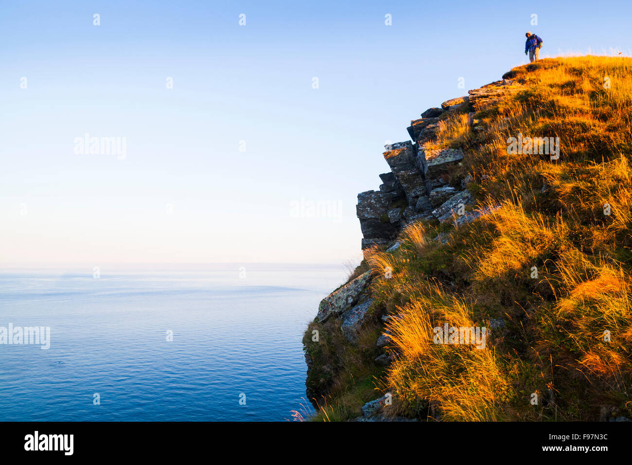 Ein Wanderer steht auf einer hohen Klippe von Vaeroy Island, Lofoten Inseln, Norwegen. Stockfoto