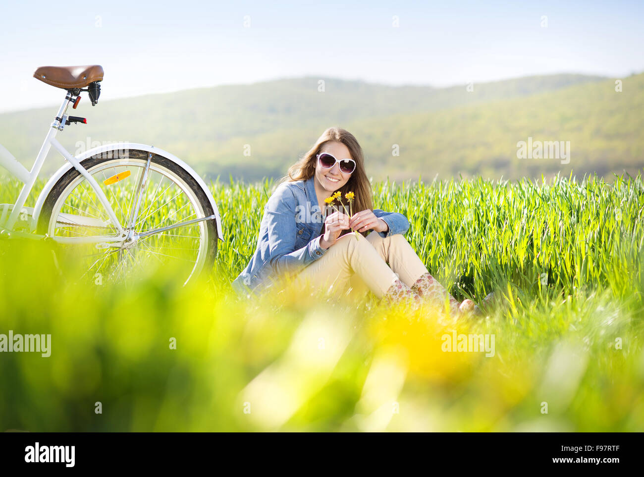 Hübsches junges Mädchen mit Fahrrad im grünen Bereich Stockfoto