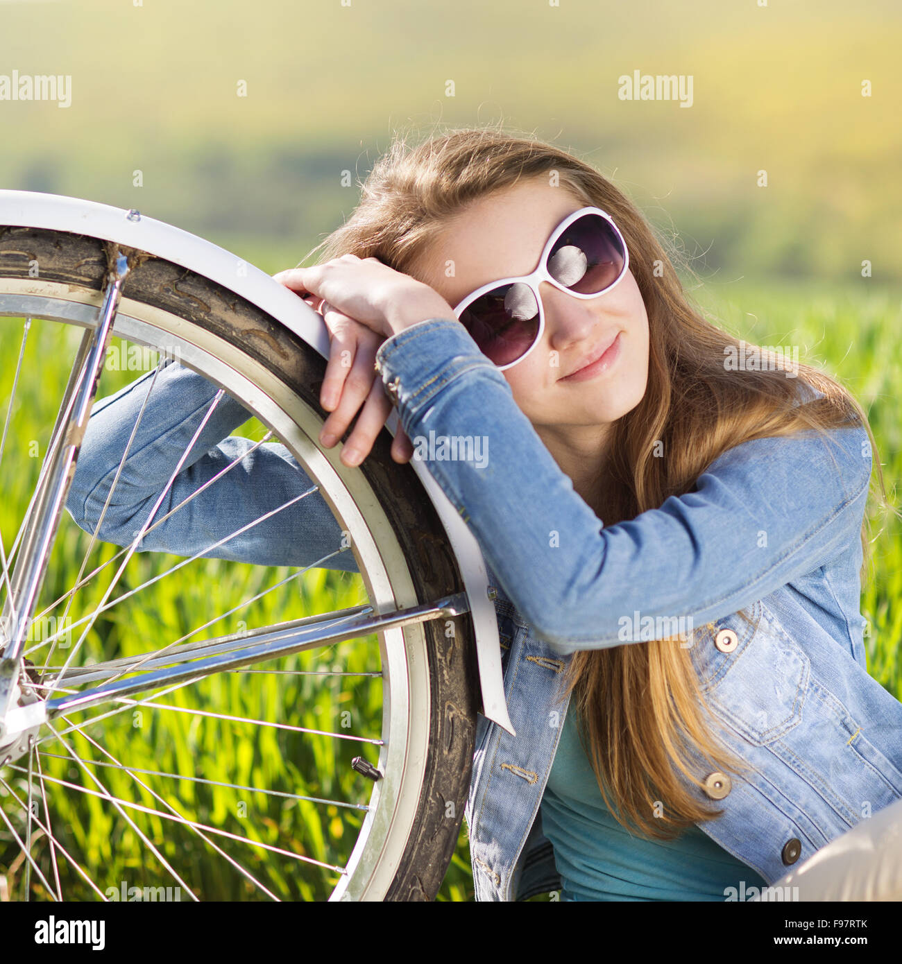 Hübsches junges Mädchen mit Fahrrad im grünen Bereich Stockfoto