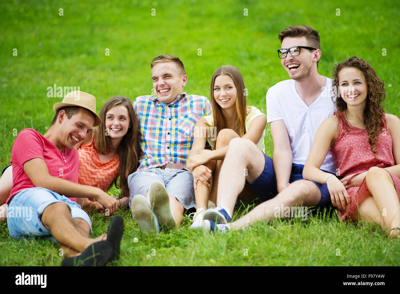 Gruppe von Jugendlichen, die Spaß im Park, sitzen auf dem Rasen Stockfoto