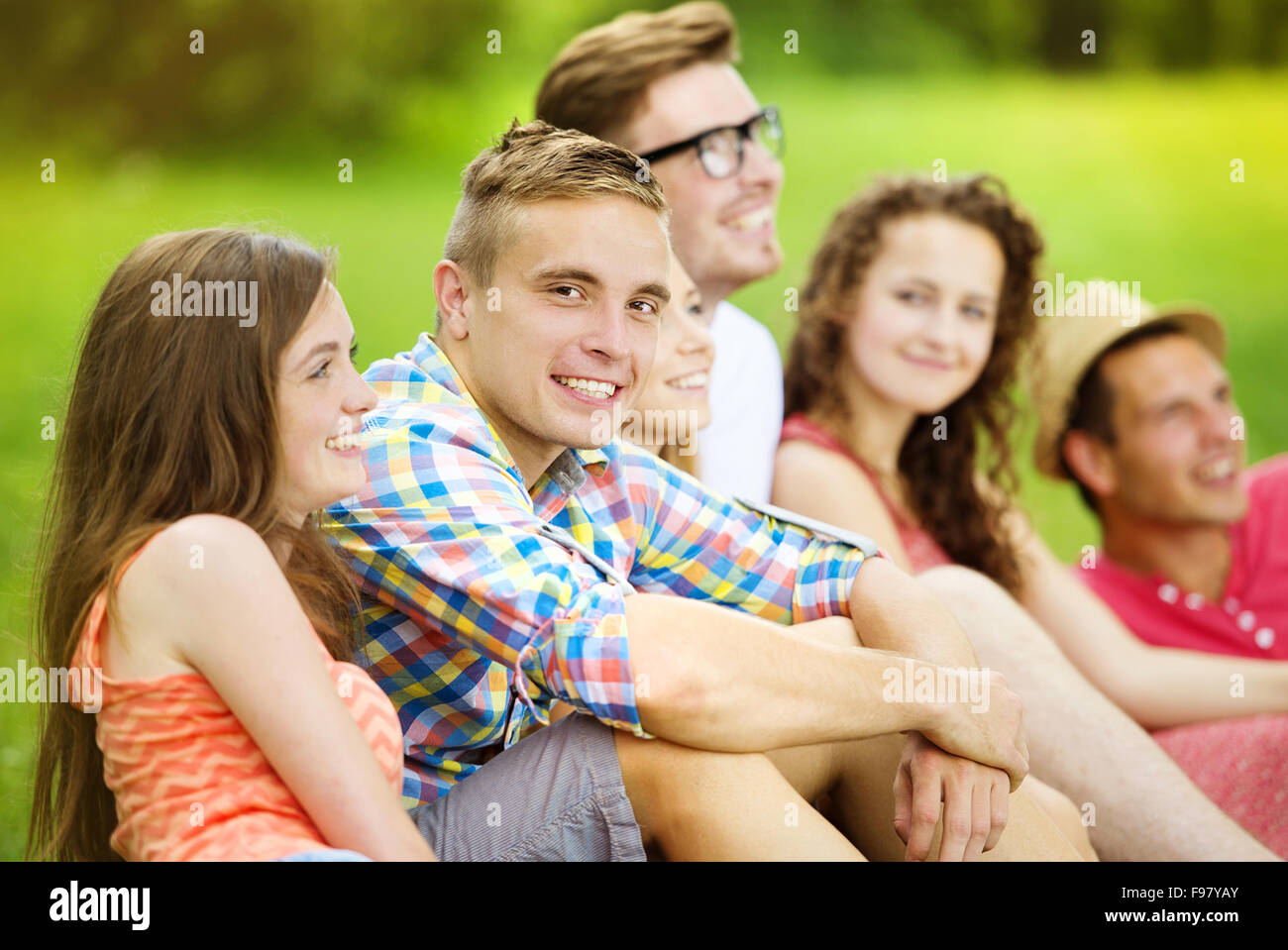 Gruppe von Jugendlichen, die Spaß im Park, sitzen auf dem Rasen Stockfoto
