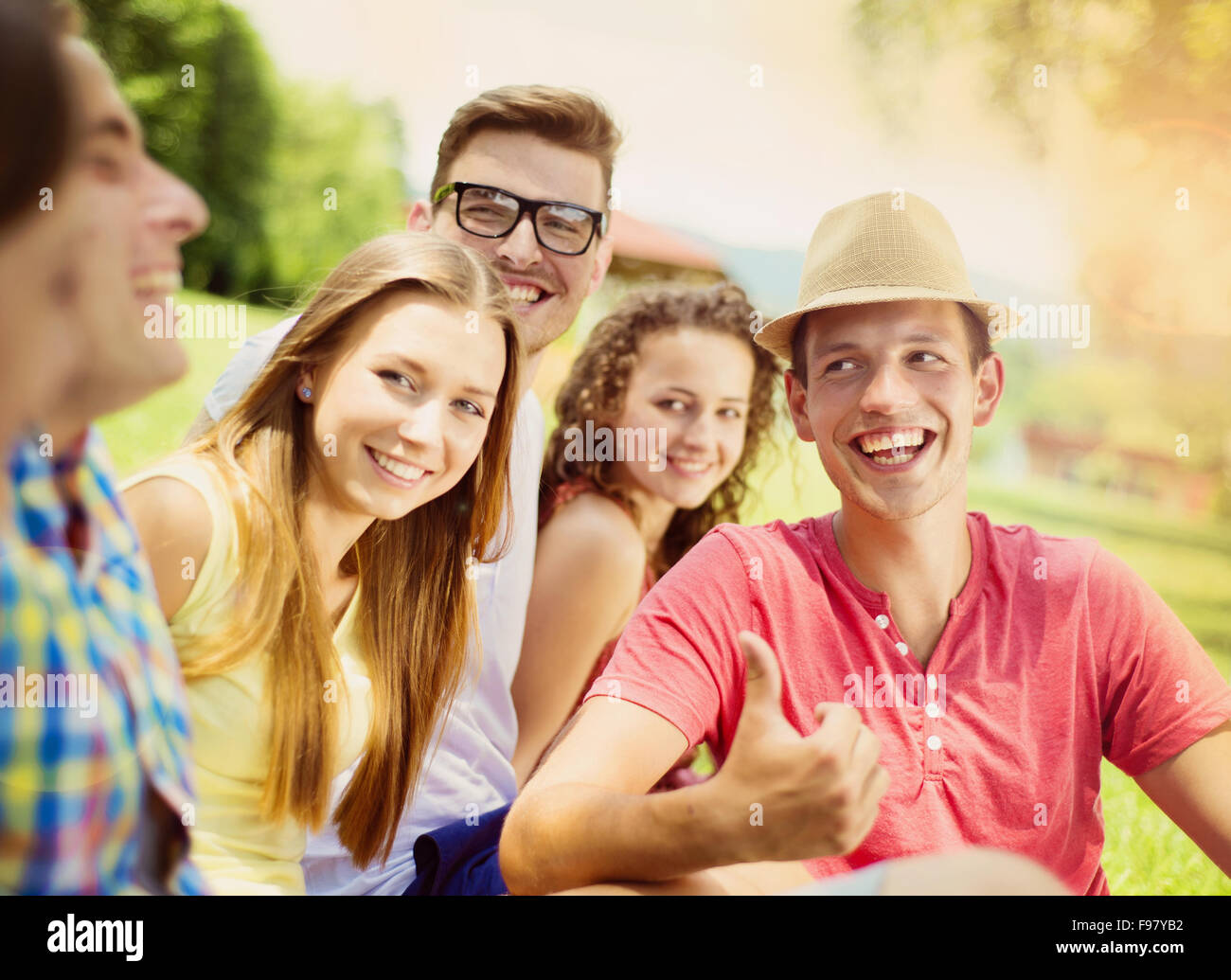 Gruppe von Jugendlichen, die Spaß im Park, sitzen auf dem Rasen Stockfoto