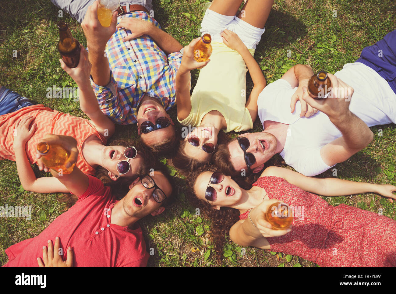 Gruppe von jungen Leuten Spaß im Park, auf dem Rasen liegend mit Getränken Stockfoto