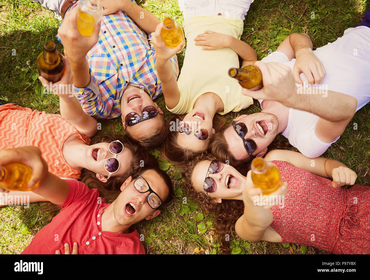 Gruppe von jungen Leuten Spaß im Park, auf dem Rasen liegend mit Getränken Stockfoto