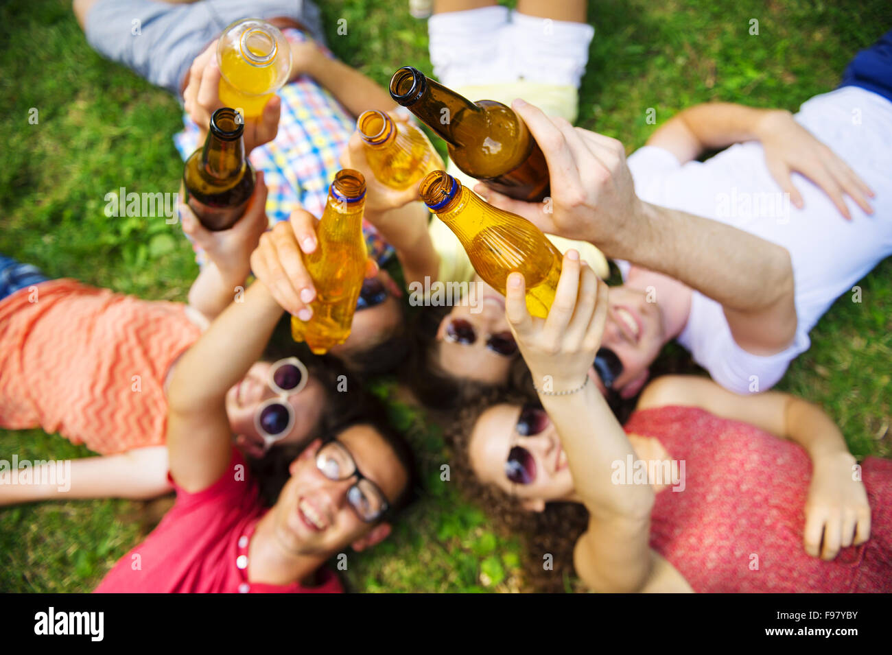 Gruppe von jungen Leuten Spaß im Park, auf dem Rasen liegend mit Getränken Stockfoto