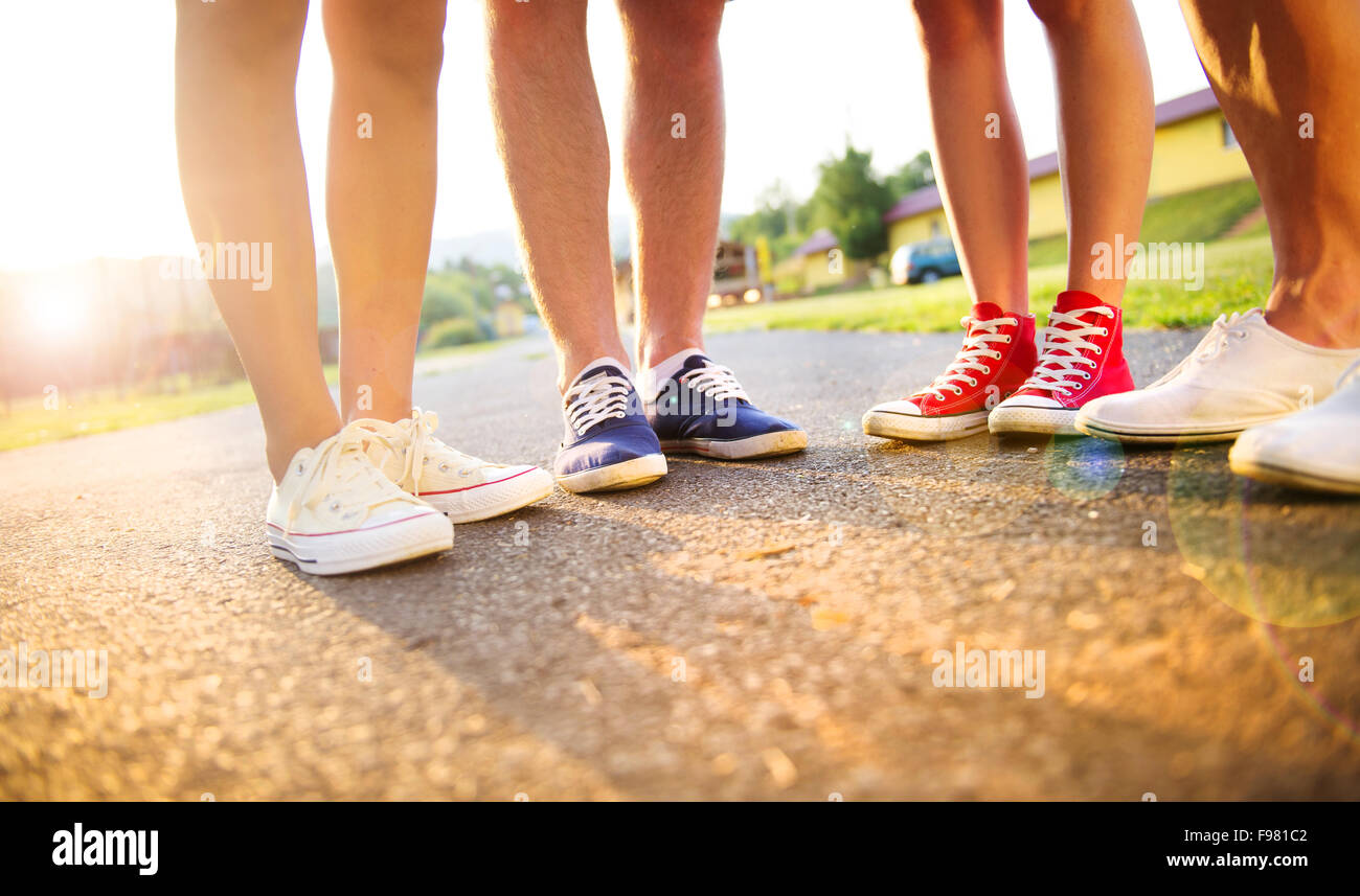 Beine und Sneakers von Teenager-Jungen und Mädchen stehen auf dem Bürgersteig Stockfoto