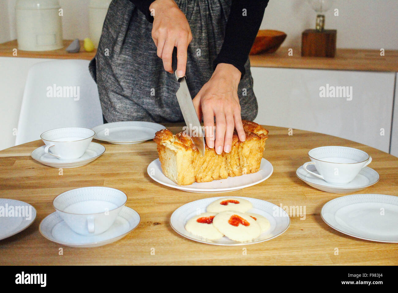Frau Schneiden von Brot auf Tisch Stockfoto