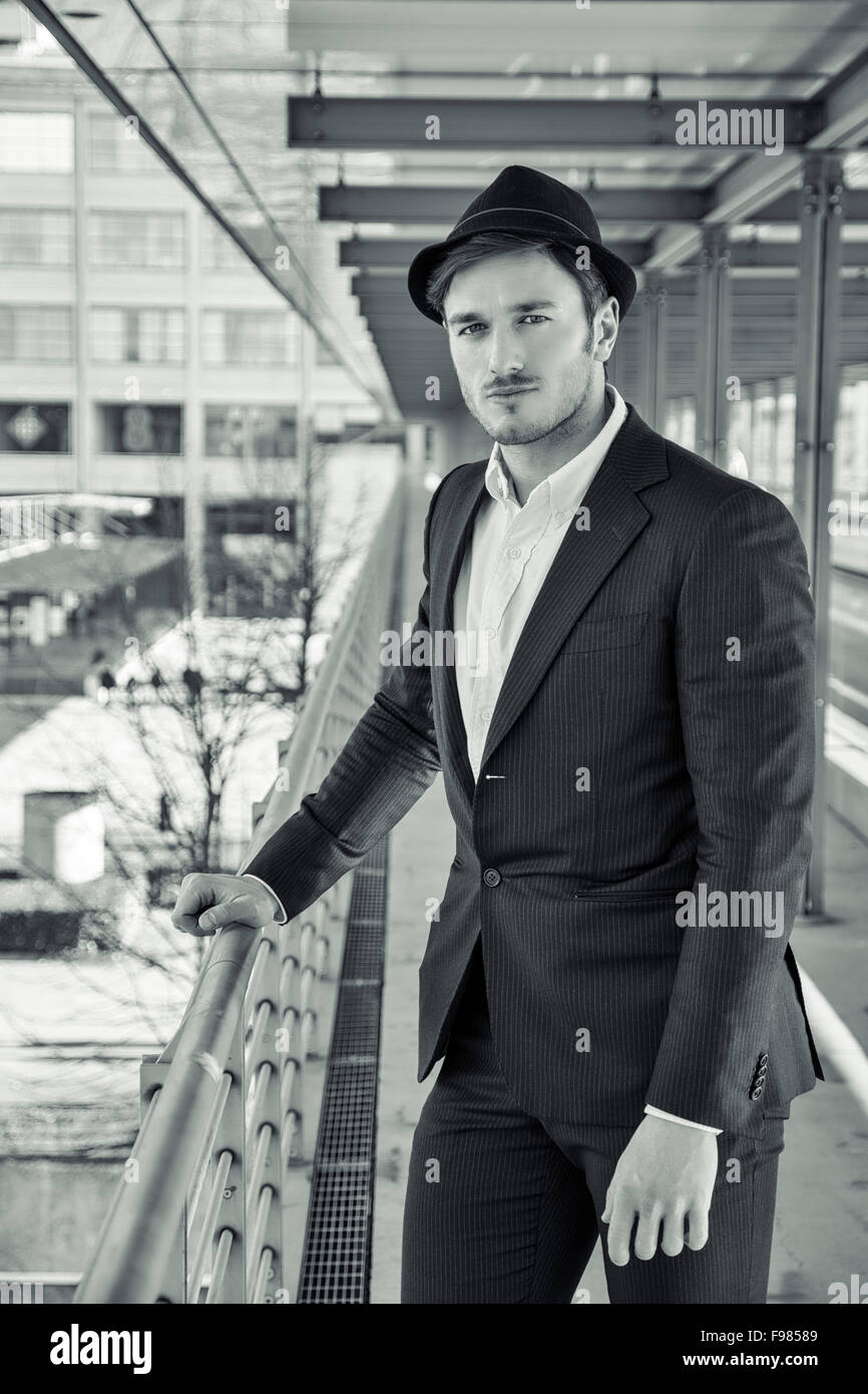 Kopf und Schultern Portrait Stylist jungen Mann tragen Anzug und Hut Blick in die Kamera stehen auf bewegte Bürgersteig in Bui Stockfoto