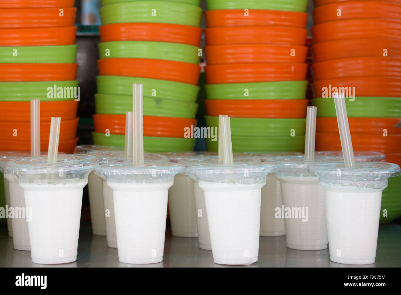 Weiße Tassen Joghurt vor orange Eine grüne Schalen Stockfoto