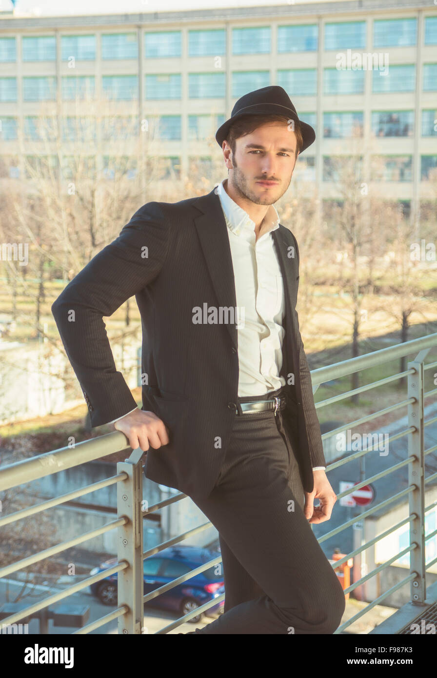 Kopf und Schultern Portrait Stylist jungen Mann tragen Anzug und Hut Blick in die Kamera stehen auf bewegte Bürgersteig in Bui Stockfoto