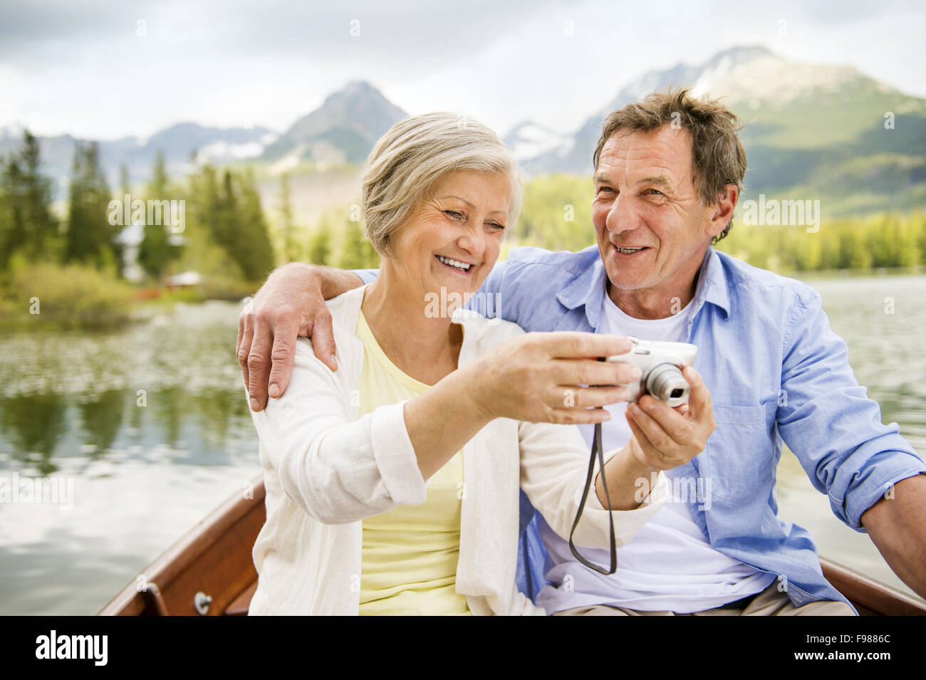 Älteres Paar auf Boot mit Bergen im Hintergrund nehmen selfie Stockfoto