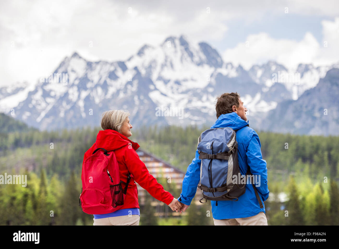 Senior-Wanderer-paar während der Spaziergang im schönen Berge, Hügel und Hotel im Hintergrund Stockfoto