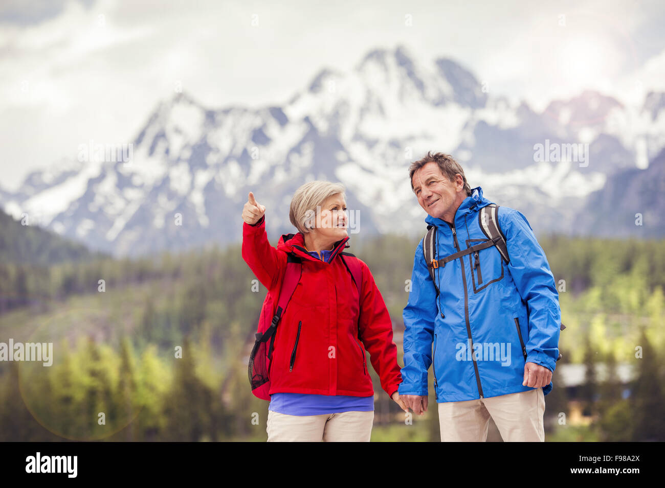 Senior-Wanderer-paar während der Spaziergang im schönen Berge, Hügel und Hotel im Hintergrund Stockfoto