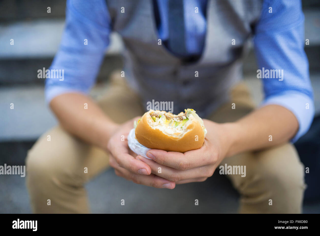 Deatil der moderne Hipster Geschäftsmann, die Mittagspause, sitzt auf der Treppe in der Stadtmitte und Burger Essen Stockfoto