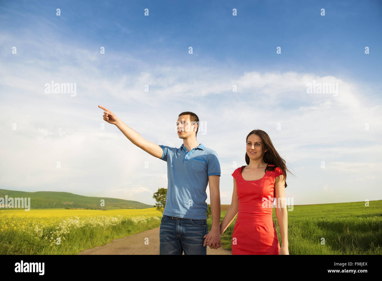 Glückliches junges Paar in Liebe zu Fuß und Hand in Hand unterwegs Landschaft neben dem Raps Feld Stockfoto
