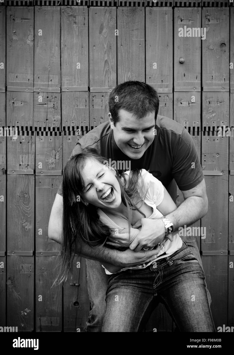 Schwarz / weiß Porträt der glückliche junge Couplehaving Spaß vor Zaun im Garten Stockfoto