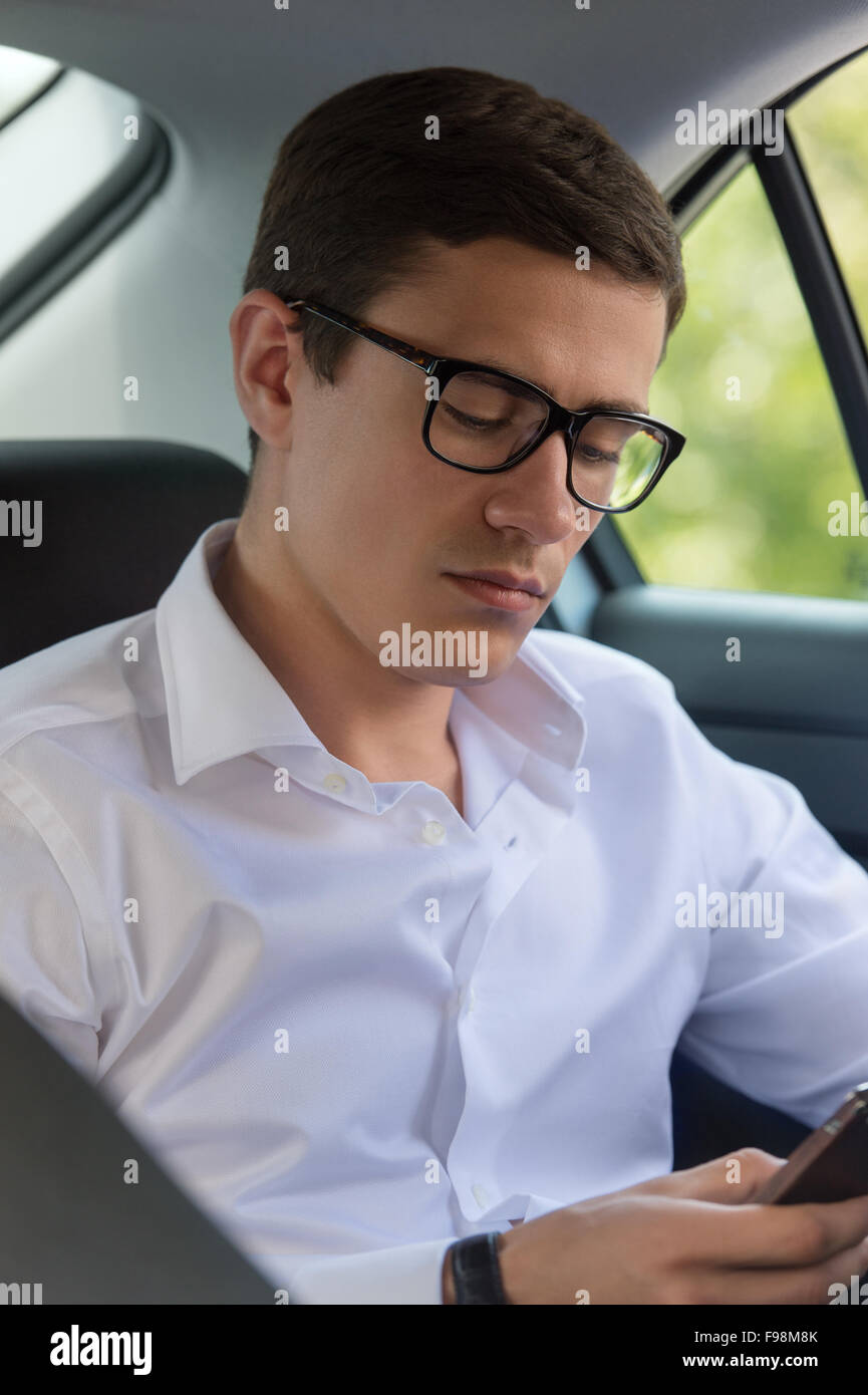 Kaukasischen Mann sitzt im Auto mit Handy in der Hand und SMS Stockfoto