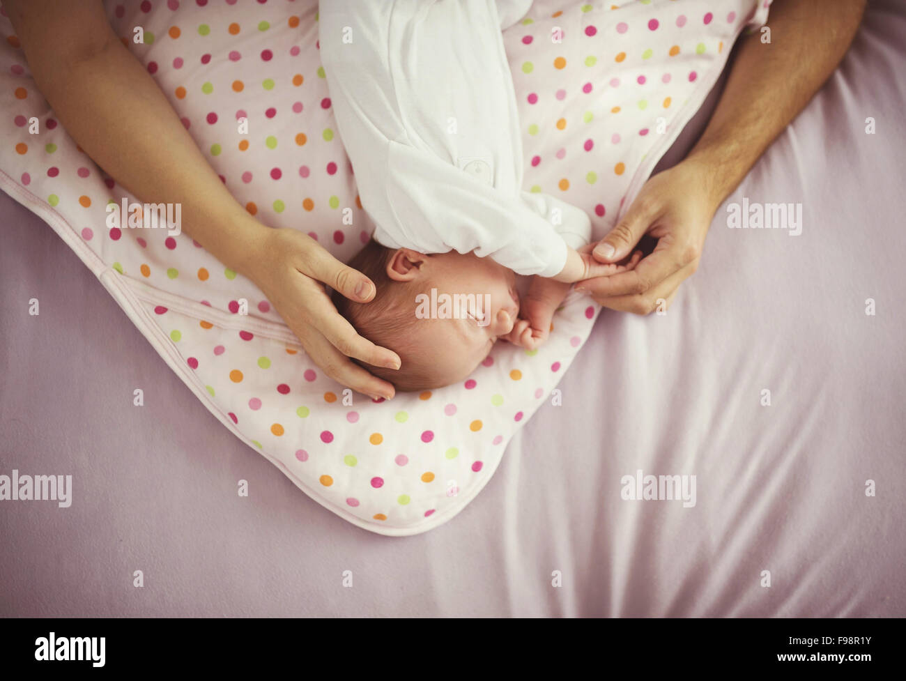Niedlichen neugeborenen Mädchen schlafend im Bett, die Hände ihrer Eltern, sie zu berühren Stockfoto