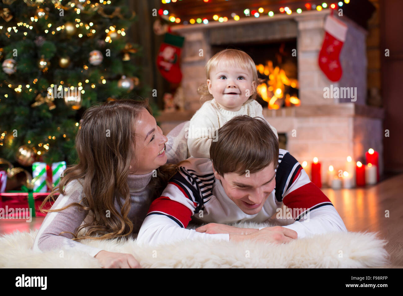 Glückliche Eltern und Kind in der Nähe von Weihnachtsbaum zu Hause spielt.  Vater, Mutter und Sohn gemeinsam feiern Neujahr Stockfoto