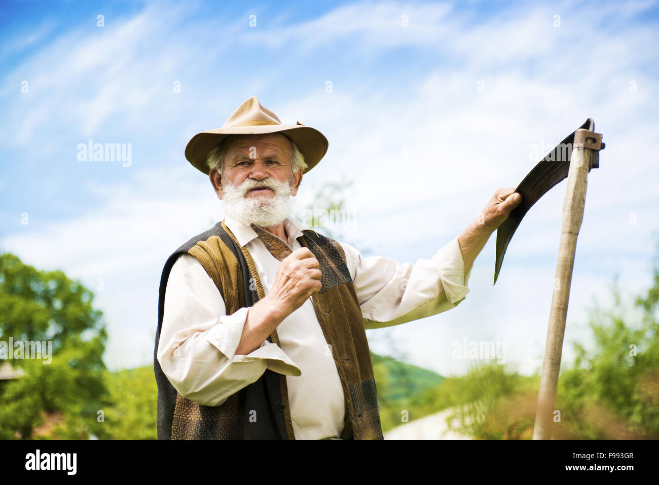 Alter Bauer mit Sense eine Pause von den Rasen mähen Stockfoto