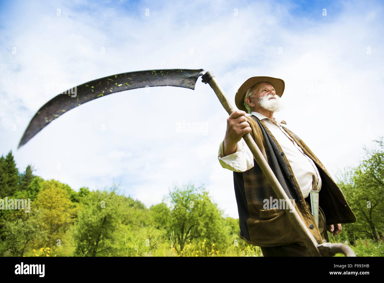Alter Bauer mit Sense eine Pause von den Rasen mähen Stockfoto