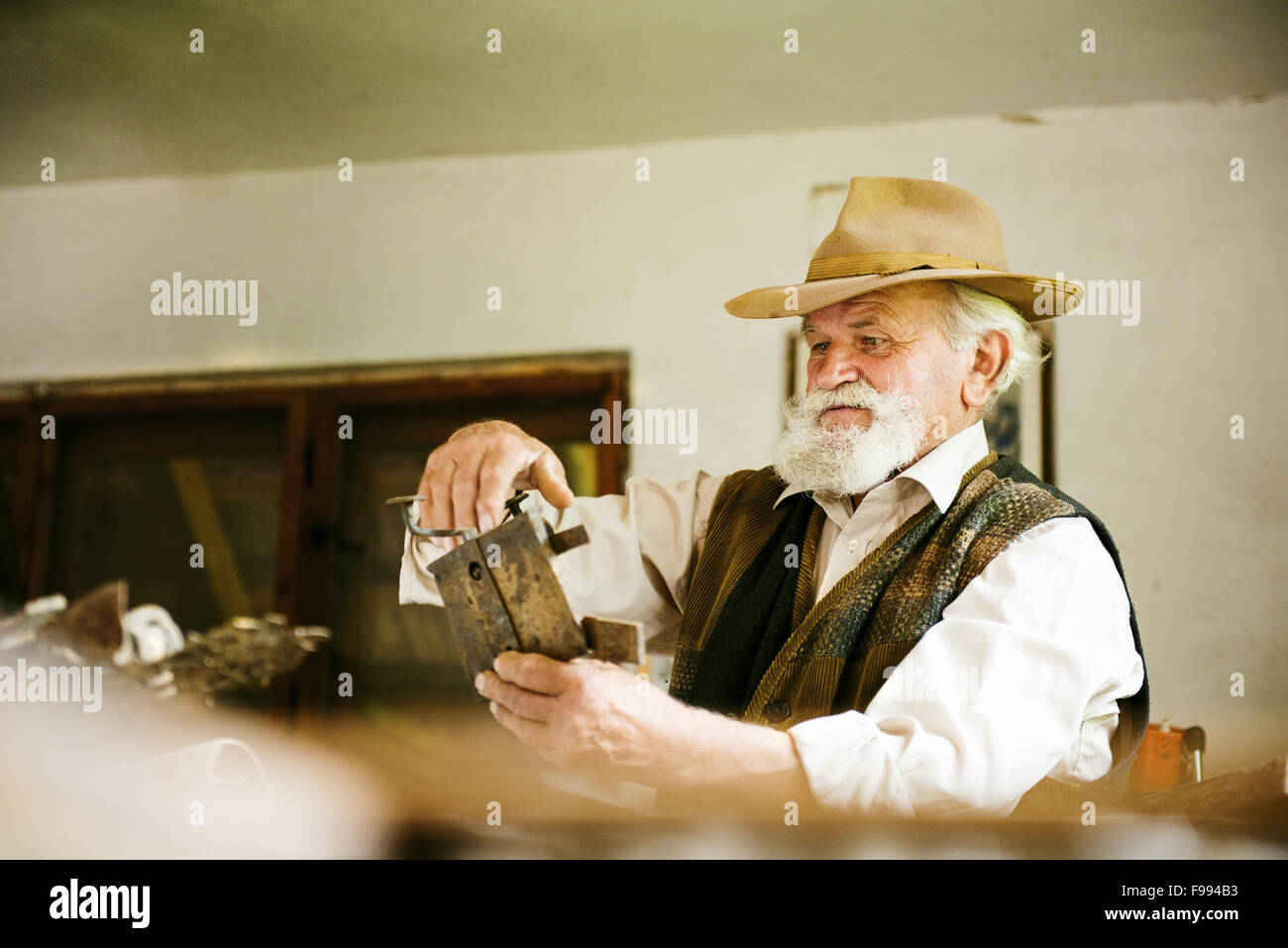 Alter Bauer mit Bart und Hut in seinem Arbeitszimmer Stockfoto