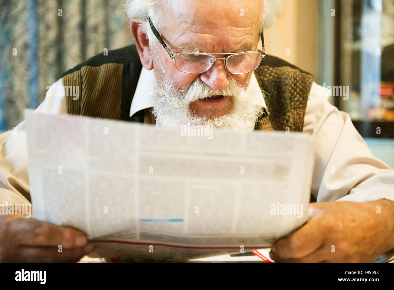 Alter Mann liest Zeitung zu Hause Stockfoto
