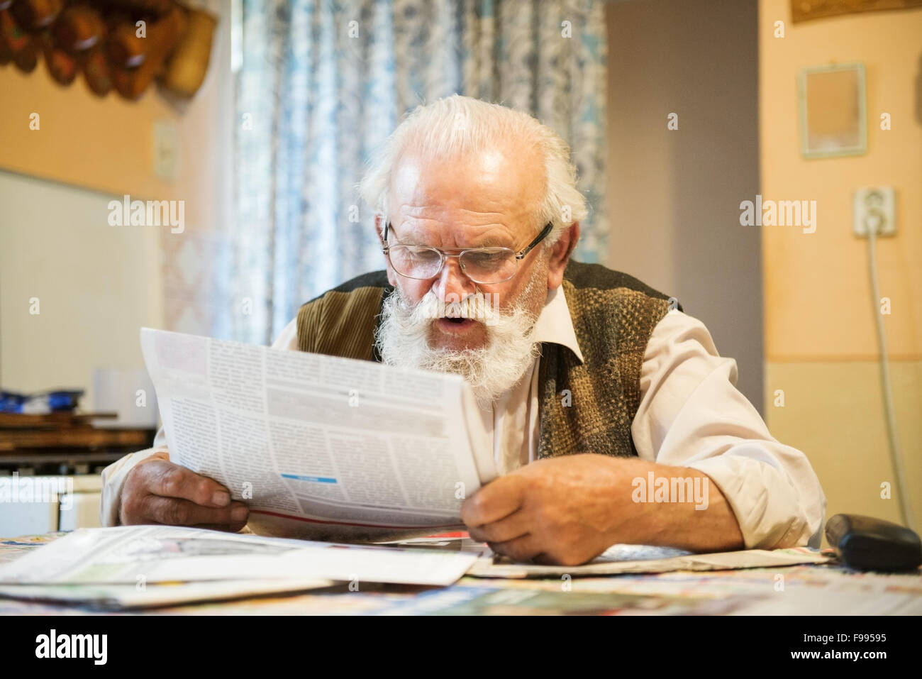 Alter Mann liest Zeitung zu Hause Stockfoto