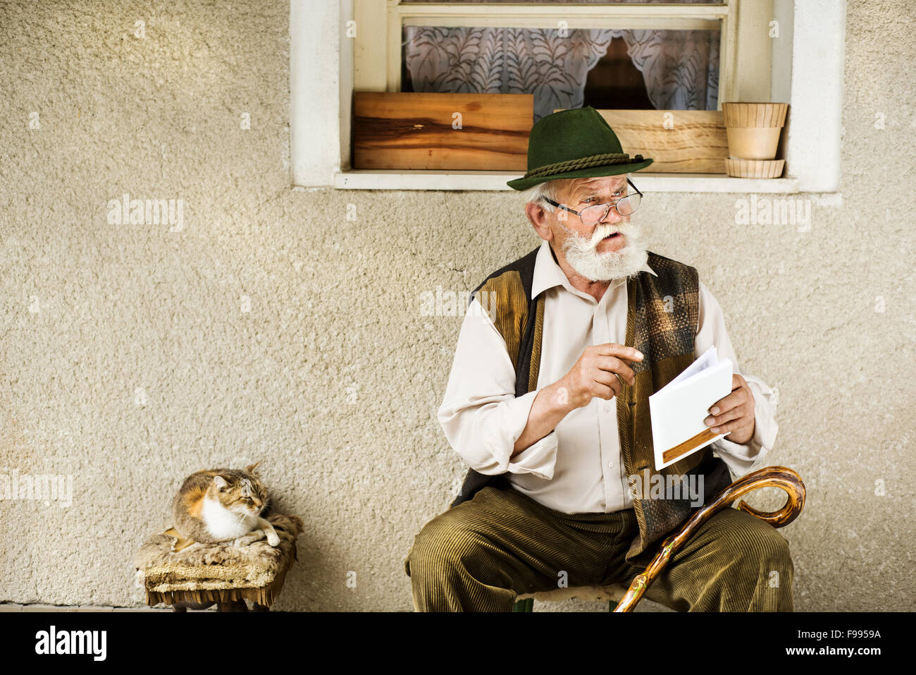 Alter Mann liest Zeitung vor seinem Haus Stockfoto