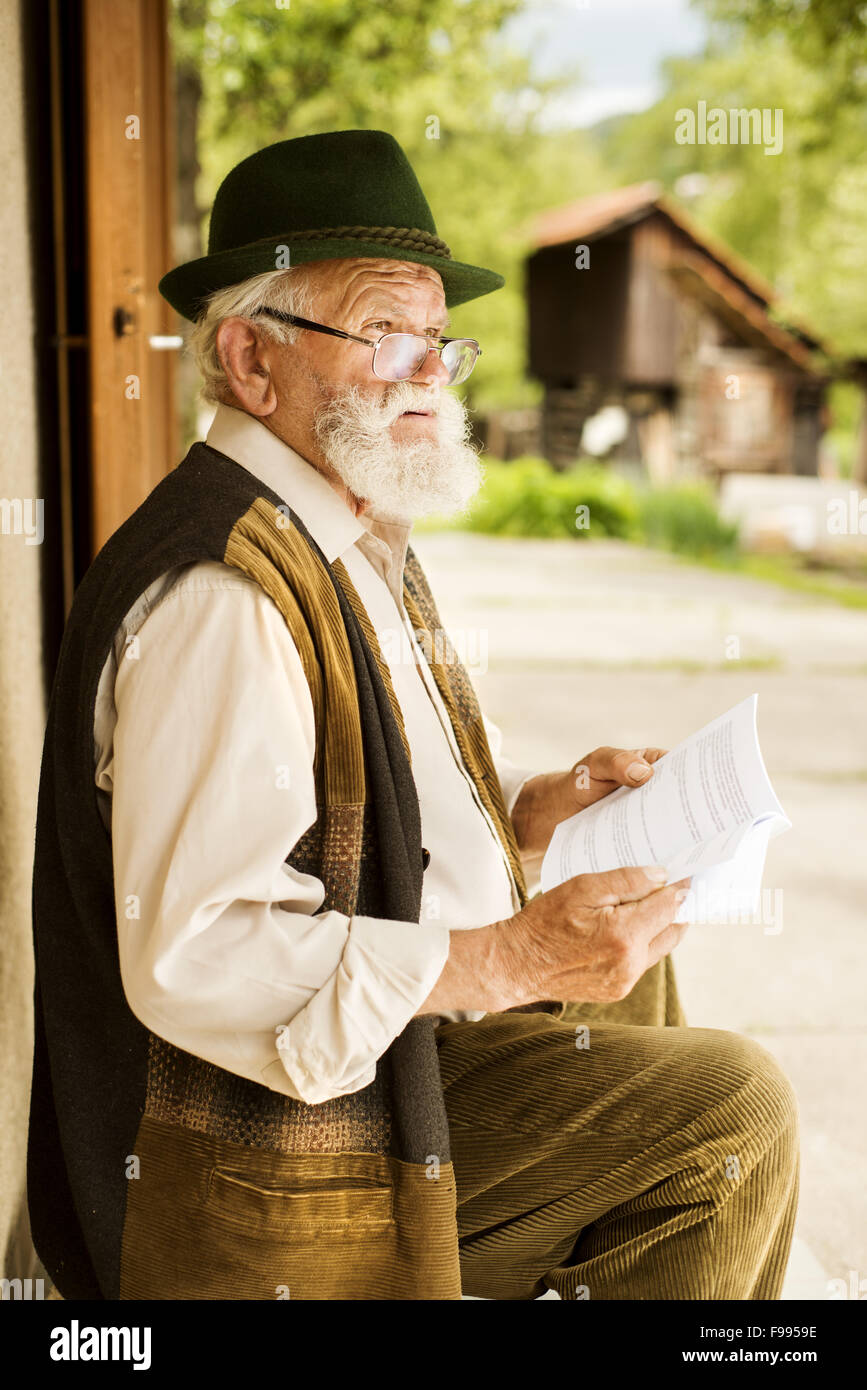 Alter Mann liest Zeitung vor seinem Haus Stockfoto