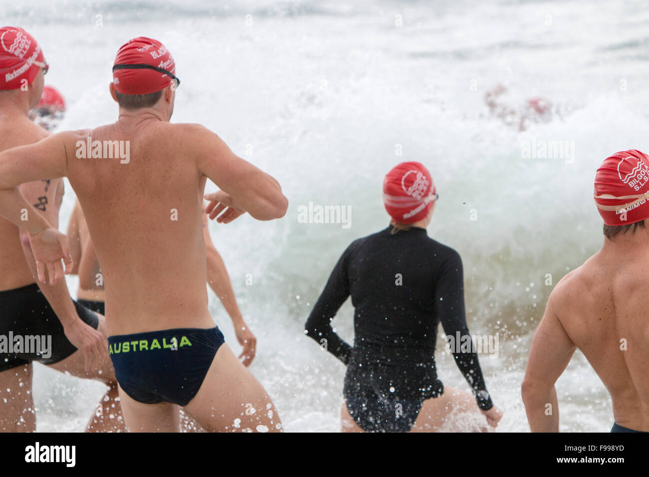 Männliche Schwimmer Rennen in die Brandung beim Bilgola Beach Männer Ocean Swim Race, Sydney, NSW, Australien, Sommer 2015 Stockfoto