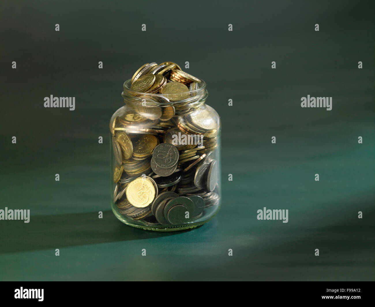 rettende Glas voller Münzen an Tafel Stockfoto