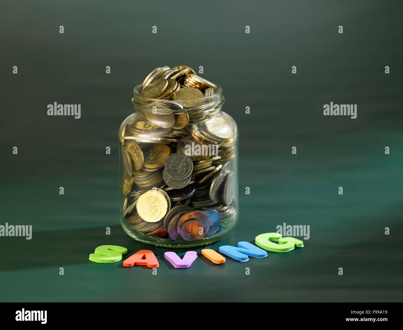rettende Glas voller Münzen an Tafel Stockfoto