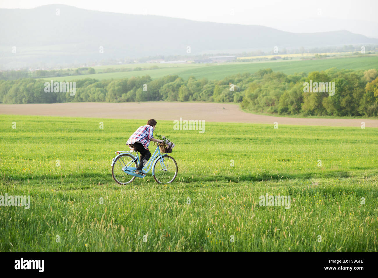 Junger Mann Reiten Vintage Fahrrad auf der grünen Wiese Stockfoto