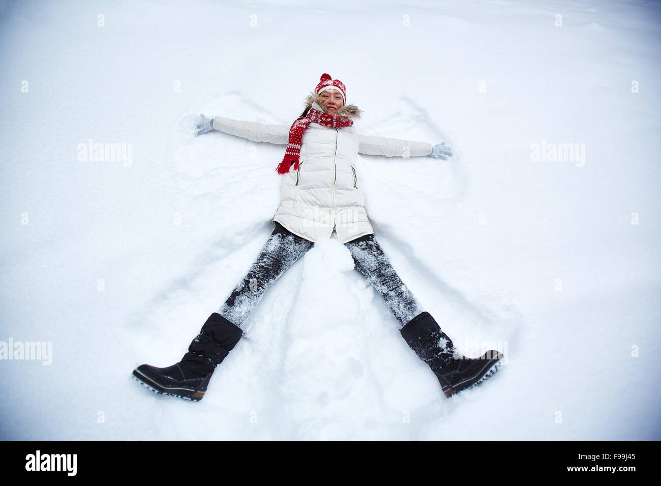 Glückliche junge Frau in Winterkleidung Lügen in Schneewehe Stockfoto