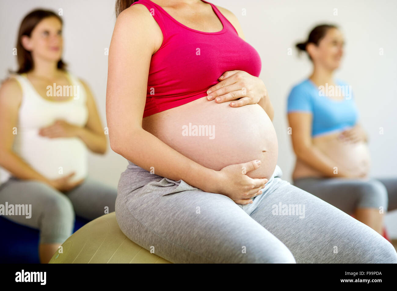 Junge schwangere Frauen tun Übung mit einem Fitnessball Stockfoto