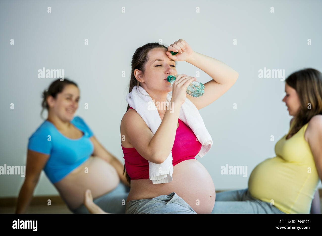 Gruppe von jungen schwangeren Womenhaving Pause während des Trainings auf Matten Stockfoto