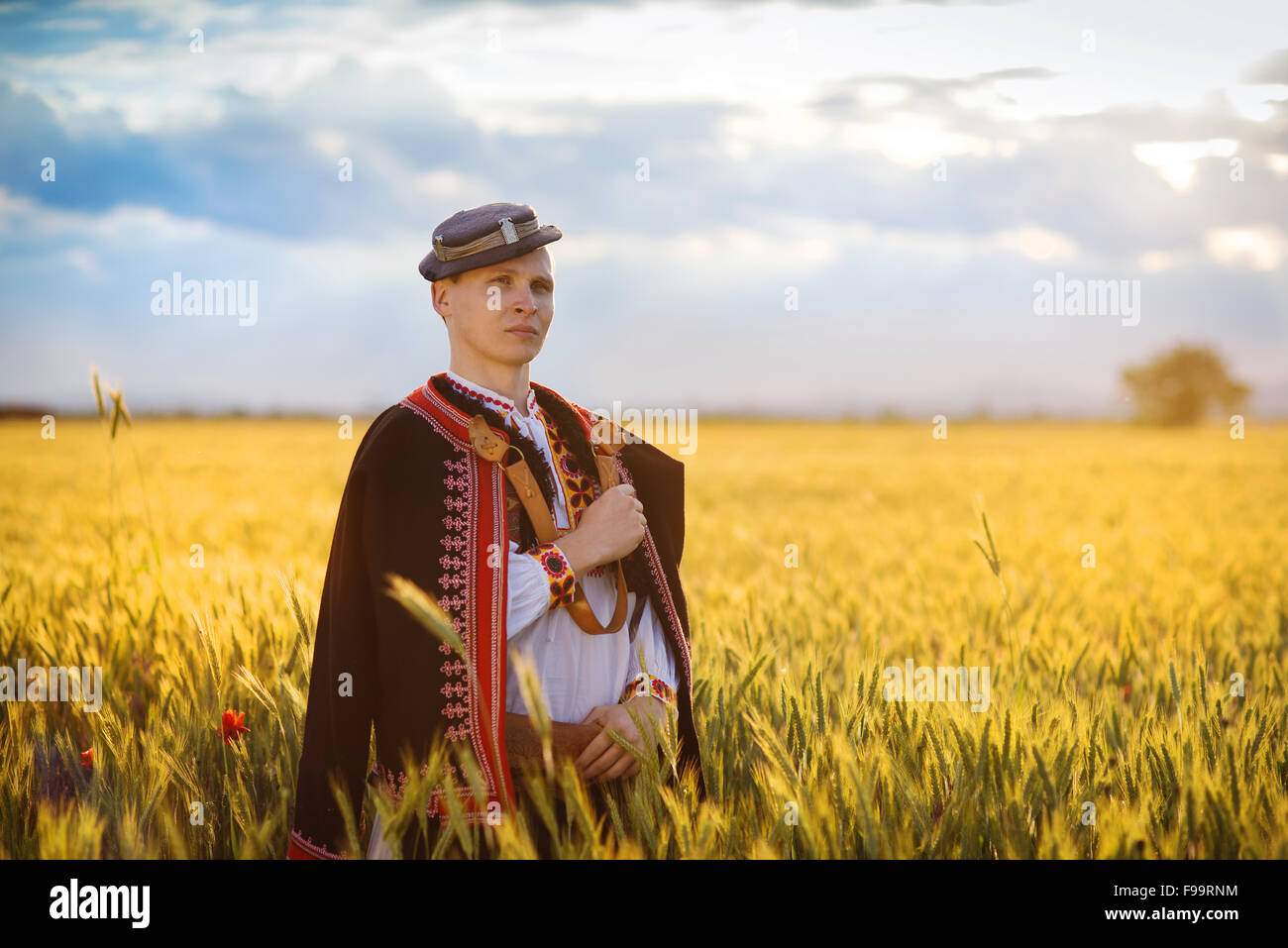 Mann im Feld Sonnenuntergang. Er ist Osteuropa Trachten tragen. Stockfoto