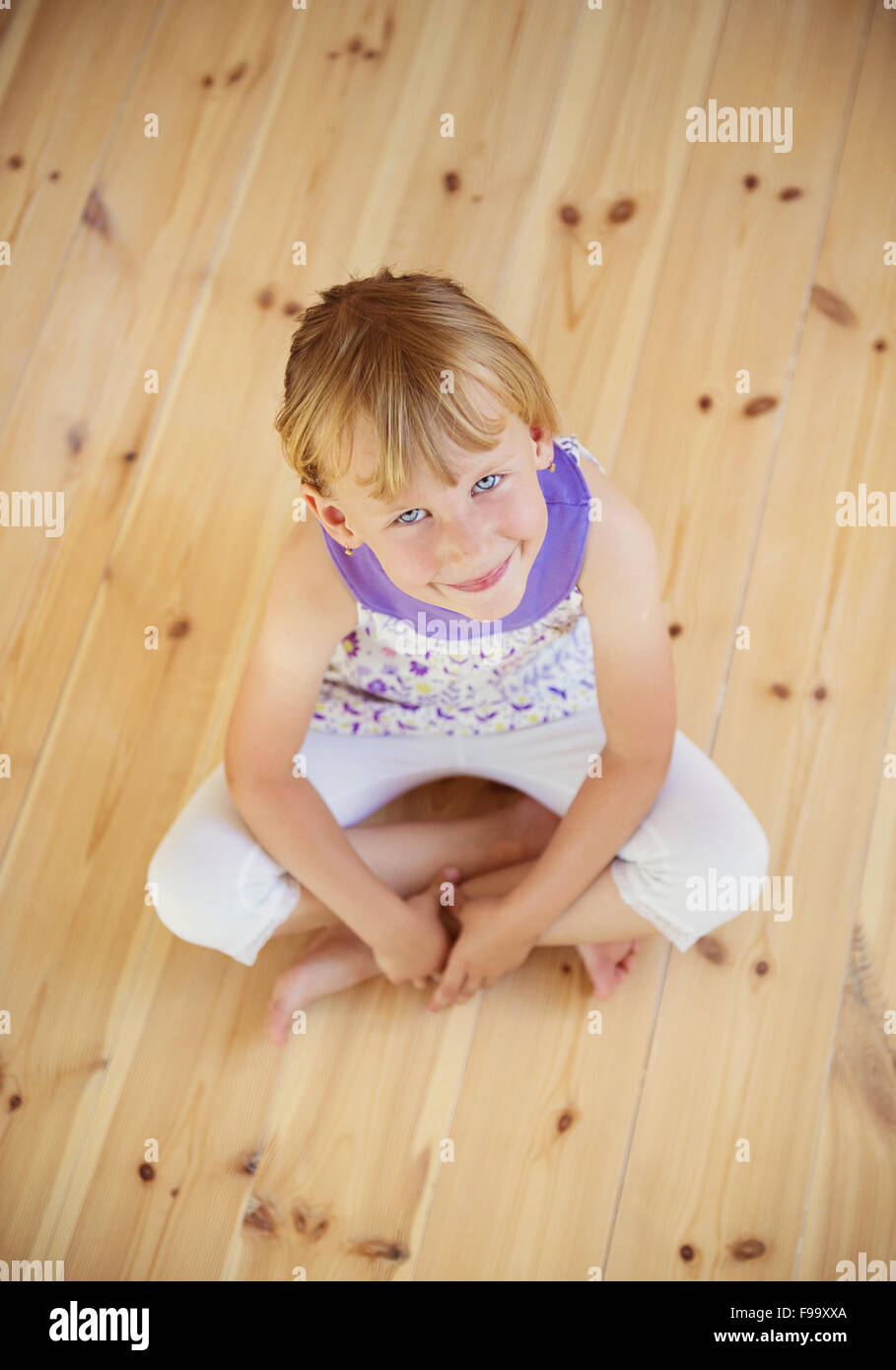 Blonde Mädchen sitzt auf dem Holzboden im Haus Stockfoto