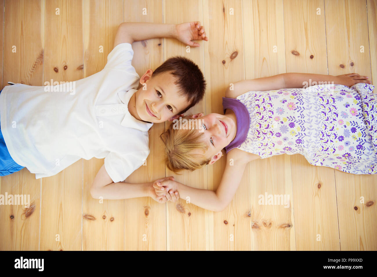 Zwei Kinder liegend auf dem Holzboden im Haus Stockfoto