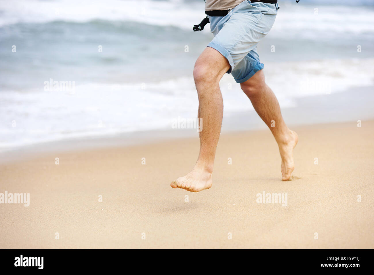 Detail der männliche Füße laufen am Sandstrand Stockfoto
