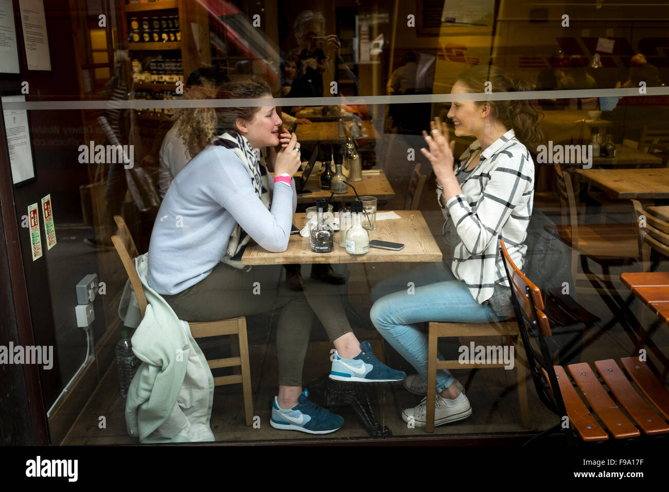 Zwei junge Freundinnen mit einem Chat in einem Café, London, UK Stockfoto