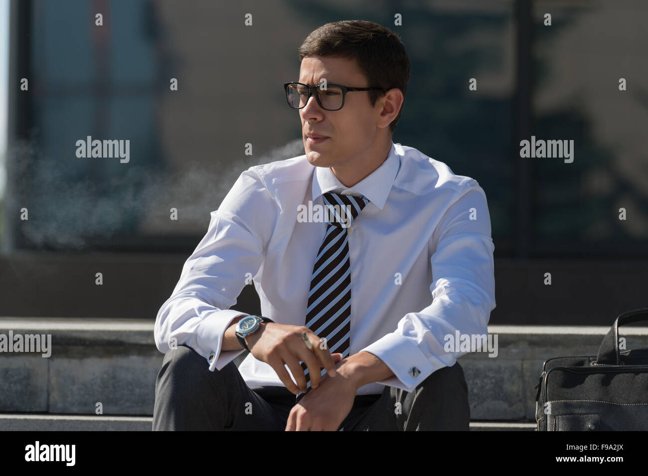 Gut gekleidete Business-Mann Rauchen sitzen auf einer Straße Bürgersteig Stockfoto